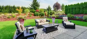A comfortable outdoor patio with modern furniture and lush garden surroundings.
