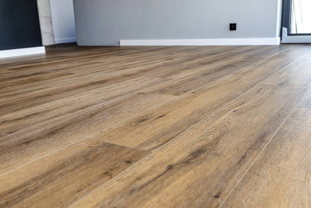 Modern vinyl panels imitating wood in the living room with selective focus and a shadow falling from the window.
